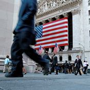 Pedestrians walk down Wall Street 