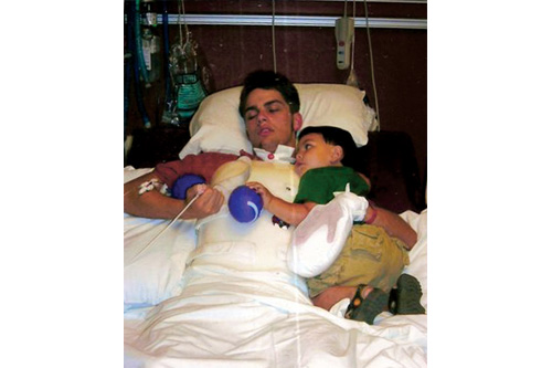 
                    Justin Logan in rehab with his son Michael. The mitt on his left hand was to prevent him from pulling out his feeding tube or hurting staff when he lashed out.
                                            (Courtesy Judi Logan)
                                        