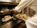 A chef places fresh turkeys in the oven