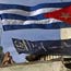A woman stands next to a Cuban flag