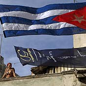 A woman stands next to a Cuban flag 