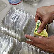 Woman puts labels on plastic containers. 