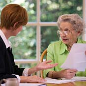 Elderly woman talks to financial adviser. 