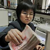 A Chinese bank teller counts 100 yuan notes 