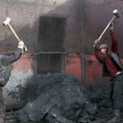 Workmen break apart coal with sledgehammers 