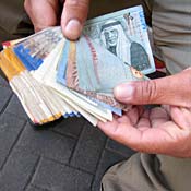 A money changer holds dinars and shekels 
