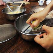 A woman grates a hunk of cheese 