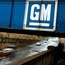 A GM sign on a steel beam above a highway