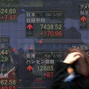 Woman walks past Nikkei on electronic stockboard 