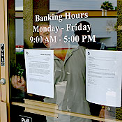 Man locks the door of a bank closed by regulators 