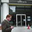 Man checks cell phone by Citibank branch