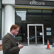 Man checks cell phone by Citibank branch 
