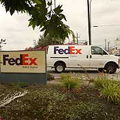 A FedEx delivery trucks leaves a FedEx facility 