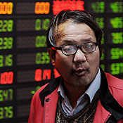 Chinese investor stands in front of a stock board 