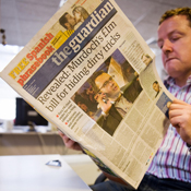A man reads a copy of the Guardian newspaper 