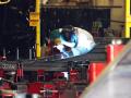 A welder works on a bus at New Flyer