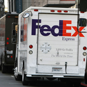 A FedEx truck is parked between two UPS trucks 