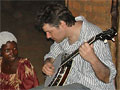 Bela performs banjo in Uganda