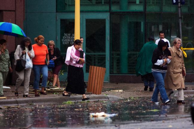 People exit the Convention Center into debris filled streets after severe weather swept through downtown Minneapolis.