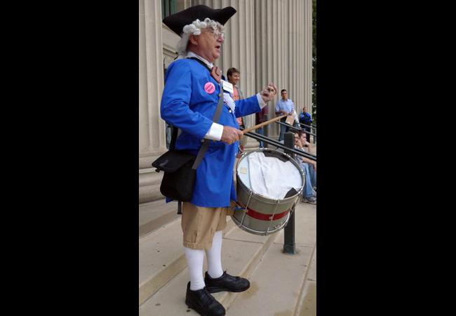Colin Wilkinson, of St. Paul, plays drums outside of Northrop Auditorium before a town hall meeting with Reps. Ron Paul and Michele Bachmann. Wilkinson, wearing a bright pink "Socialism Sucks" button, said he came to the event to show his support for young conservative students.