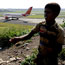 An Indian Airlines plane takes off as a boy plays