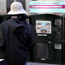 A pedestrian at a newspaper vending rack