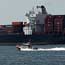 A U.S. Coast Guard vessel passes a container ship