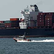 A U.S. Coast Guard vessel passes a container ship 