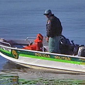 A green police trooper rides a boat in Brazil.