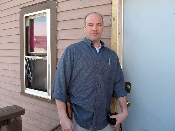 Officer Mike Dollarschell of the St. Paul Police collects more photographic evidence from a crime scene outside a victim's home during one of his First Light visits.