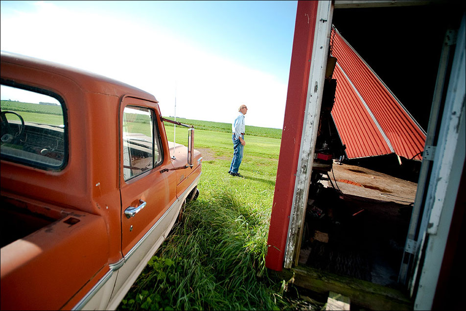 Richard Mauch, a World War II veteran and former farmer, surveys the damage to his machine shed from a storm the night before. Both the east and north walls were blown out. Living on a fixed income, he and his wife already live a very thrifty lifestyle and accept assistance through a federally funded food box program. They hope their insurance will cover the cost of the damage.