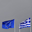EU and Greek flags are pictured under a heavy sky in Athens on Oct. 10, 2011.