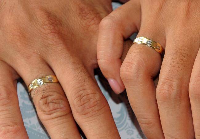 Photo A couple holds hands showing their wedding rings during a mass 