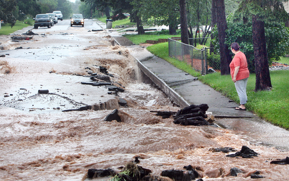 Water flows down a damaged street