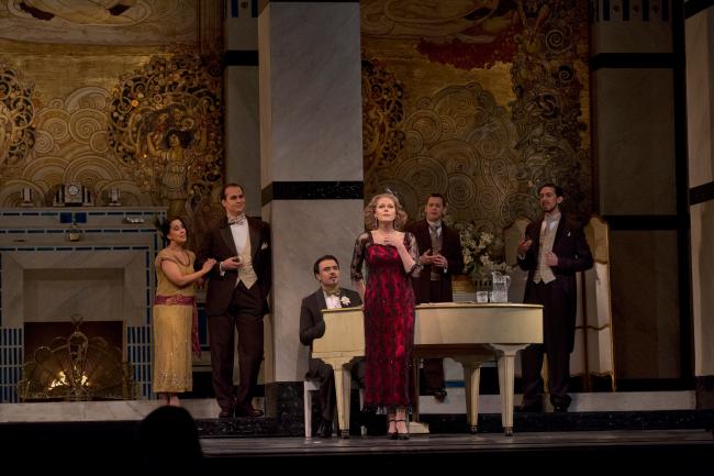 A scene from Puccini's Kristine Opolais (center) as Magda with Monica Yunus as Yvette, Edward Parks as Perichaud, Marius Brenciu as Prunier, Keith Jameson as Gobin, and Evan Hughes as Crebillon in Puccini's "La Rondine." (Ken Howard/Metropolitan Opera)