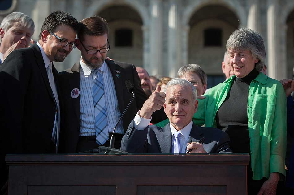 Minnesota's old, white, male governor gives a thumbs-up after signing the bill.